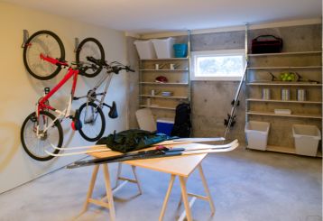 Organized garage in Cedar Hill, TX, featuring wall-mounted bike racks, open shelving with bins and sports gear, and a central worktable for projects.