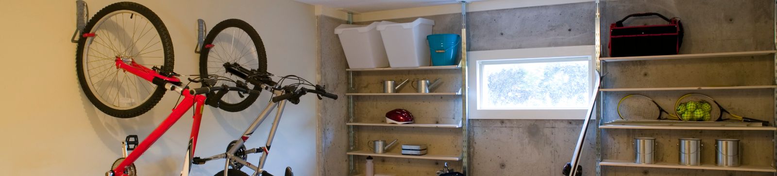 Organized garage in Cedar Hill, TX, featuring wall-mounted bike racks, open shelving with bins and sports gear, and a central worktable for projects.
