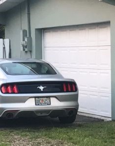 Silver car parked in front of a garage with a newly realigned white sectional garage door.