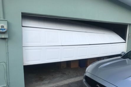 Close-up of a misaligned garage door panel with visible gaps and uneven alignment.