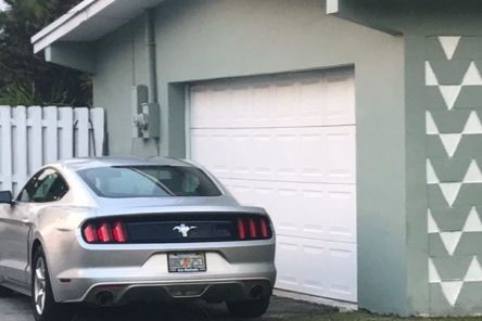 Wide shot of a Fort Worth home with a repaired white garage door and a silver car in the driveway.