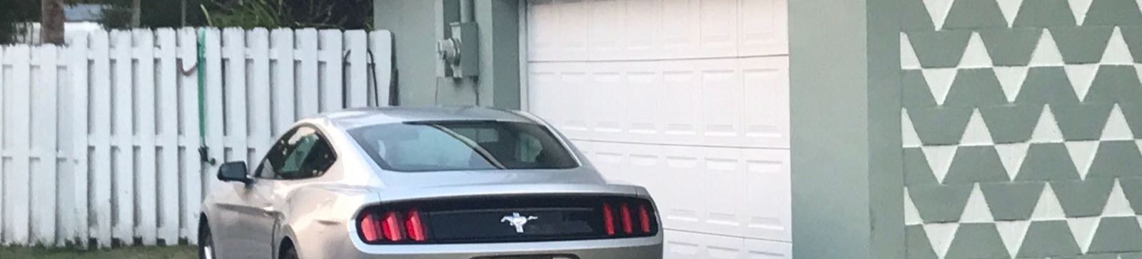 Silver car parked in front of a garage with a newly realigned white sectional garage door.