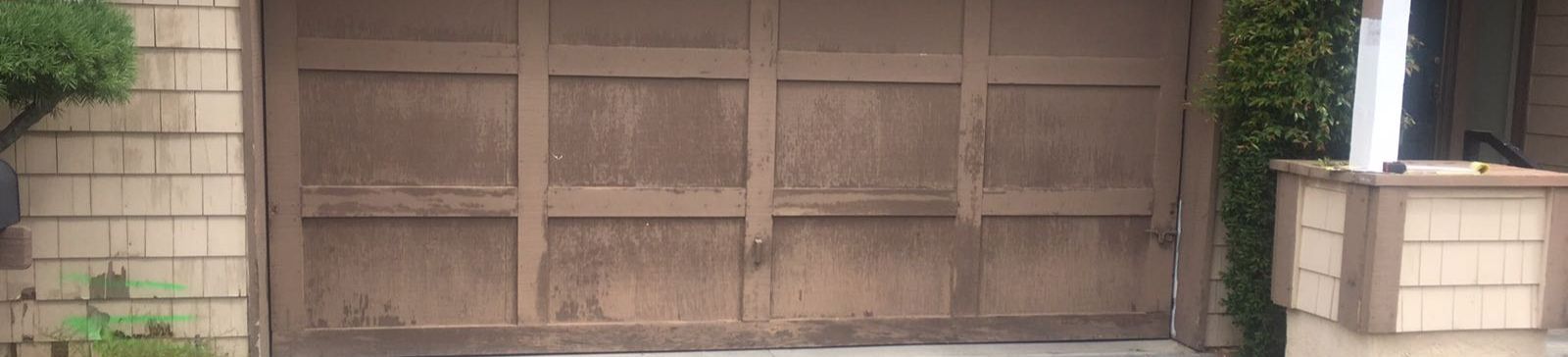 Old, weathered wooden garage door with peeling paint on a Dallas home before replacement.