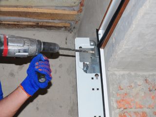 Technician Installing New Garage Door Track – Cedar Hill, TX Close-up of a technician in blue gloves using a power drill to secure a metal garage door track to the wall during a new garage door installation in Cedar Hill, TX.
