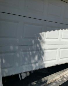 Close-up of off-track overhead garage door partially detached from guide rail in Cedar Hill