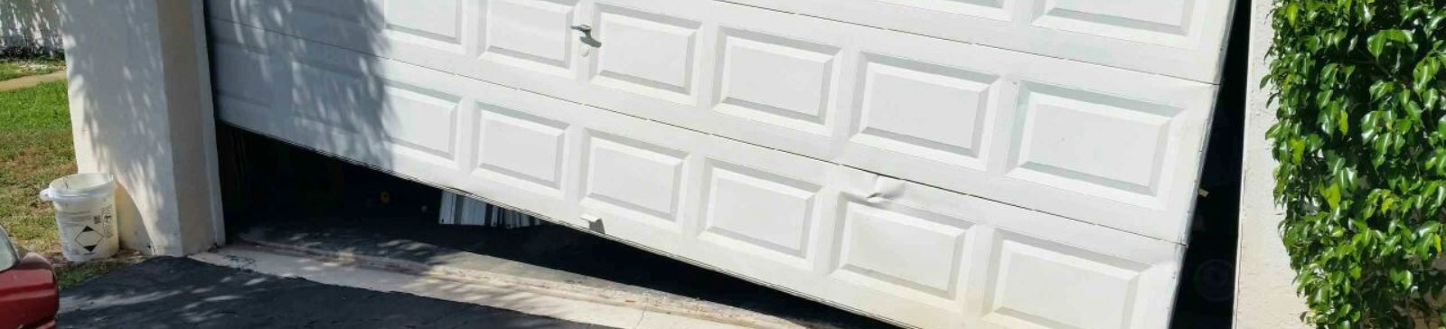 Damaged white garage door misaligned and off its lower track section – Cedar Hill project