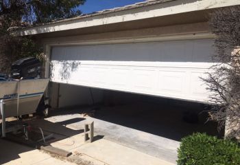 Damaged garage door off its tracks and leaning – Cedar Hill garage repair scene