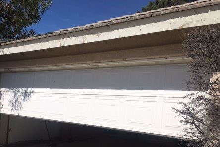 Damaged garage door off its tracks and leaning – Cedar Hill garage repair scene