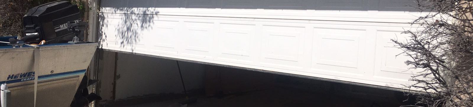Damaged garage door off its tracks and leaning – Cedar Hill garage repair scene
